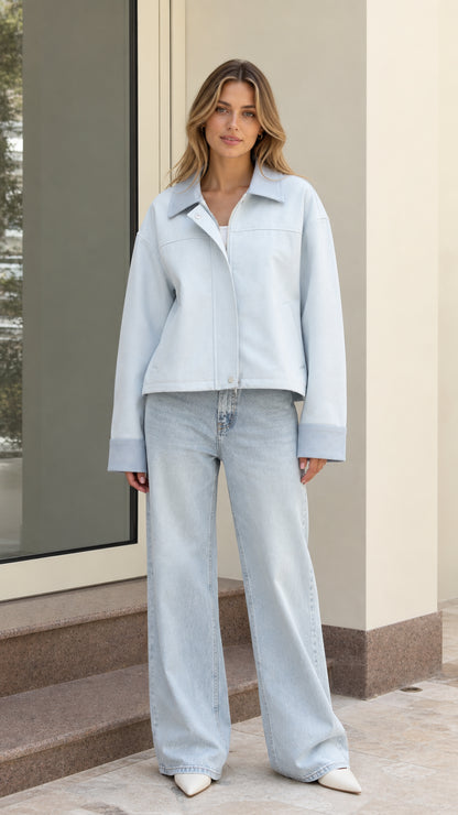 Front view of model wearing light blue cropped zip-up utility jacket with light wash jeans