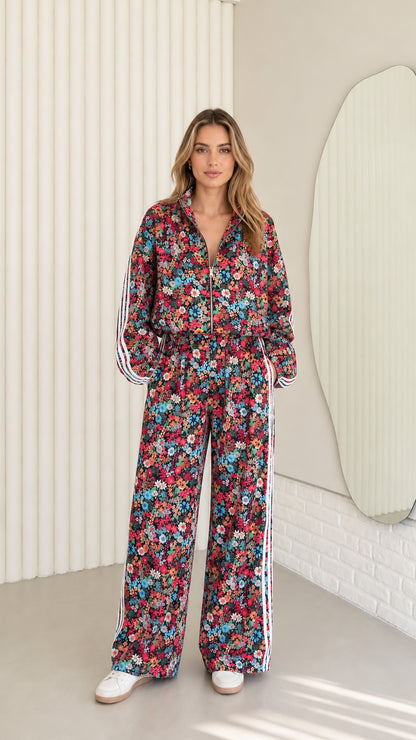 Front full view of woman wearing burgundy floral print zip-up tracksuit set