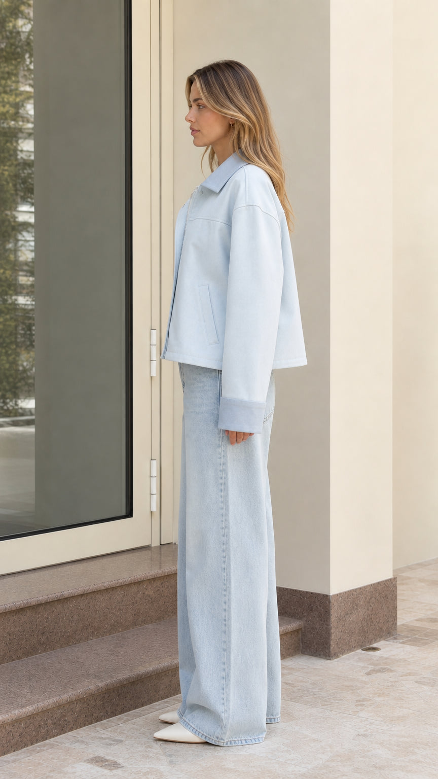 Side profile of model wearing light blue boxy cropped jacket and wide-leg denim