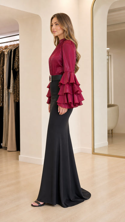 Model wearing burgundy ruffle sleeve blouse and black mermaid skirt side profile