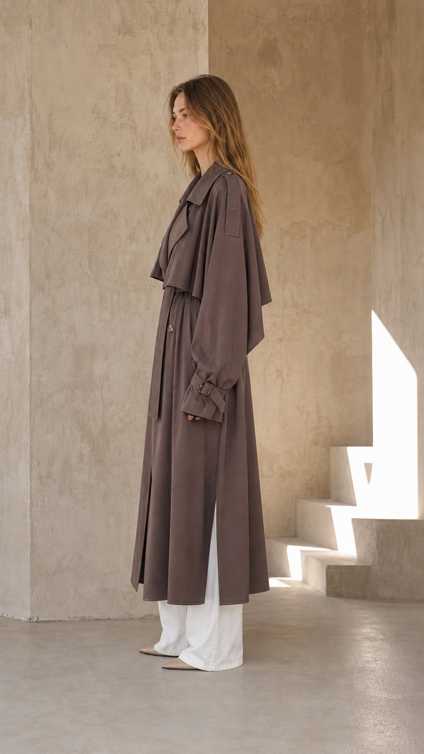 Side profile of woman wearing dark taupe long trench coat