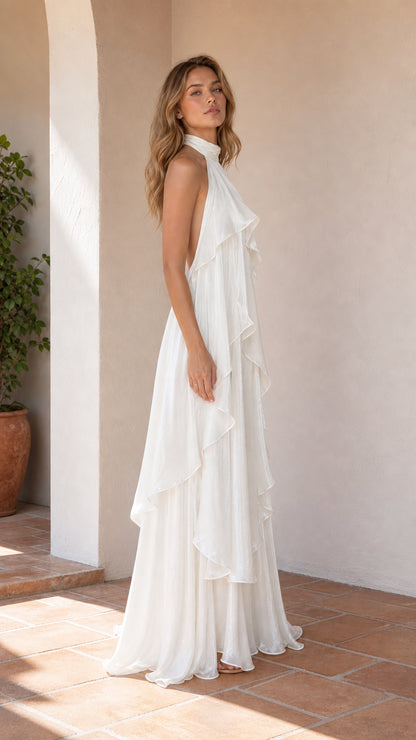 Side profile view of model in white halter maxi dress