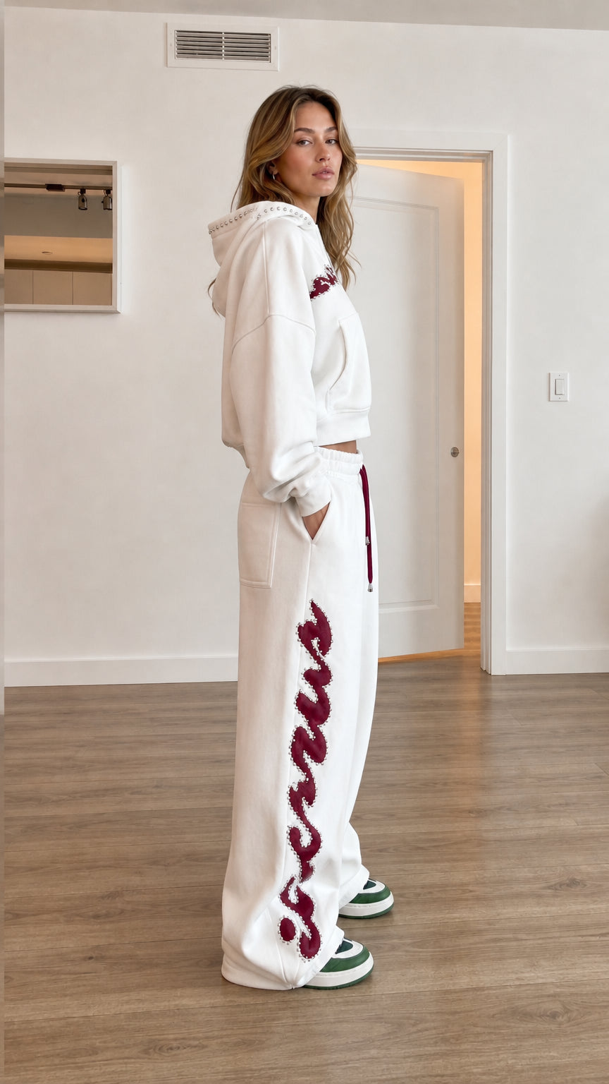 Side profile view of model wearing white wide leg sweatpants with graphic detail