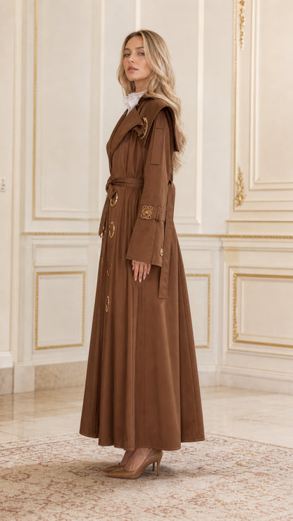 Side profile view of woman wearing long brown maxi trench coat