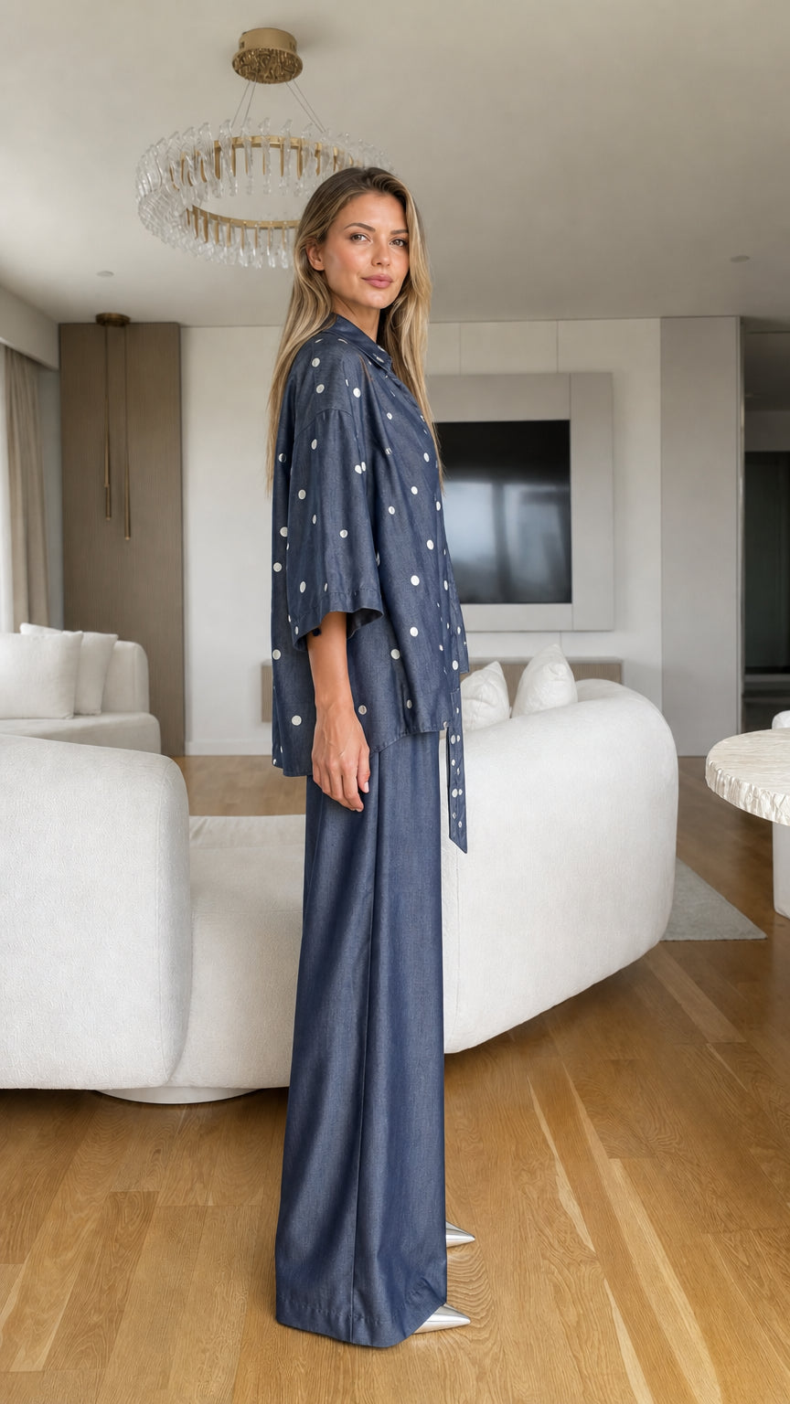 Model wearing denim blue polka dot two-piece outfit side profile view