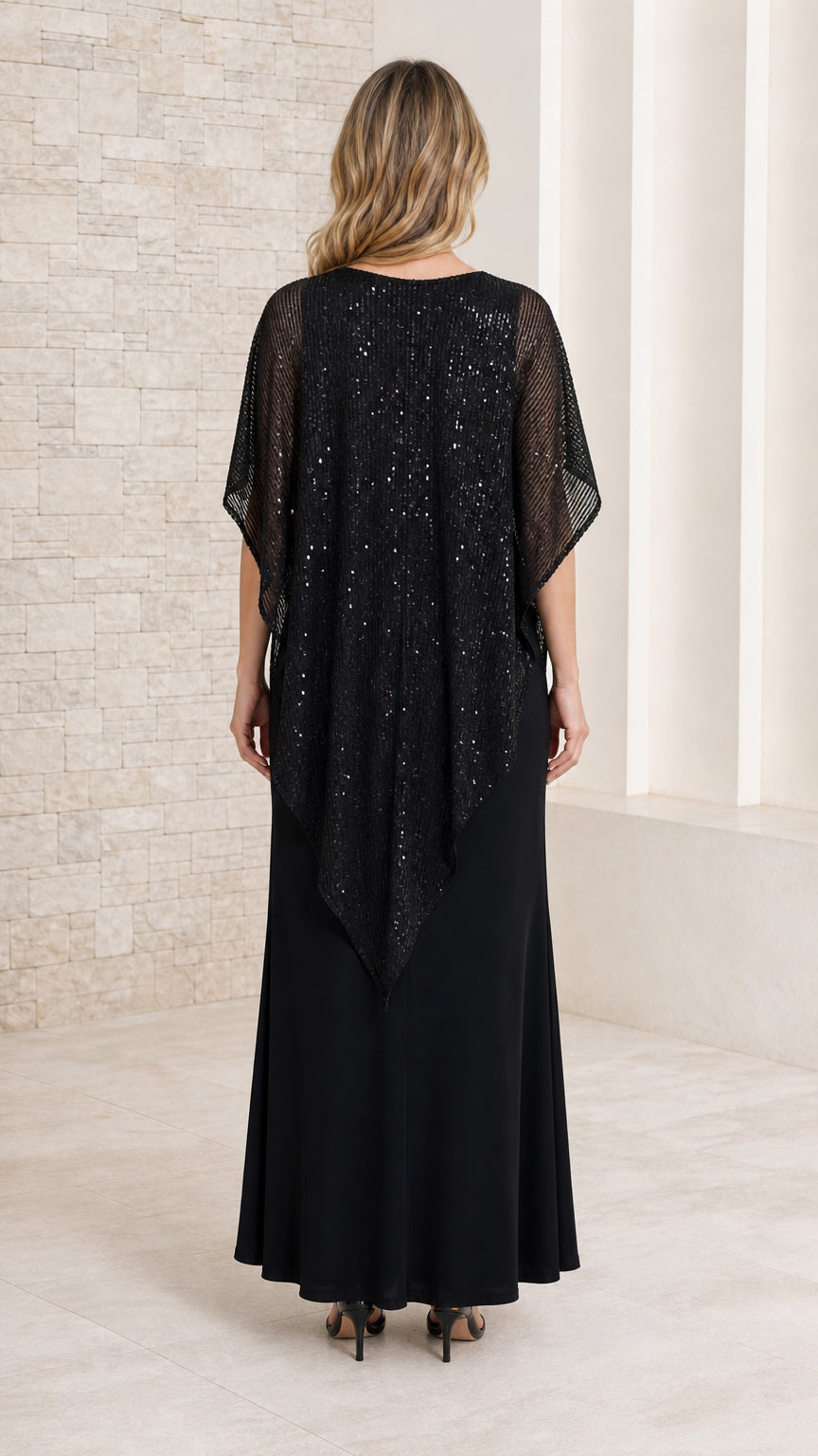 Back view of model wearing floor-length black formal dress with sheer sequined cape overlay