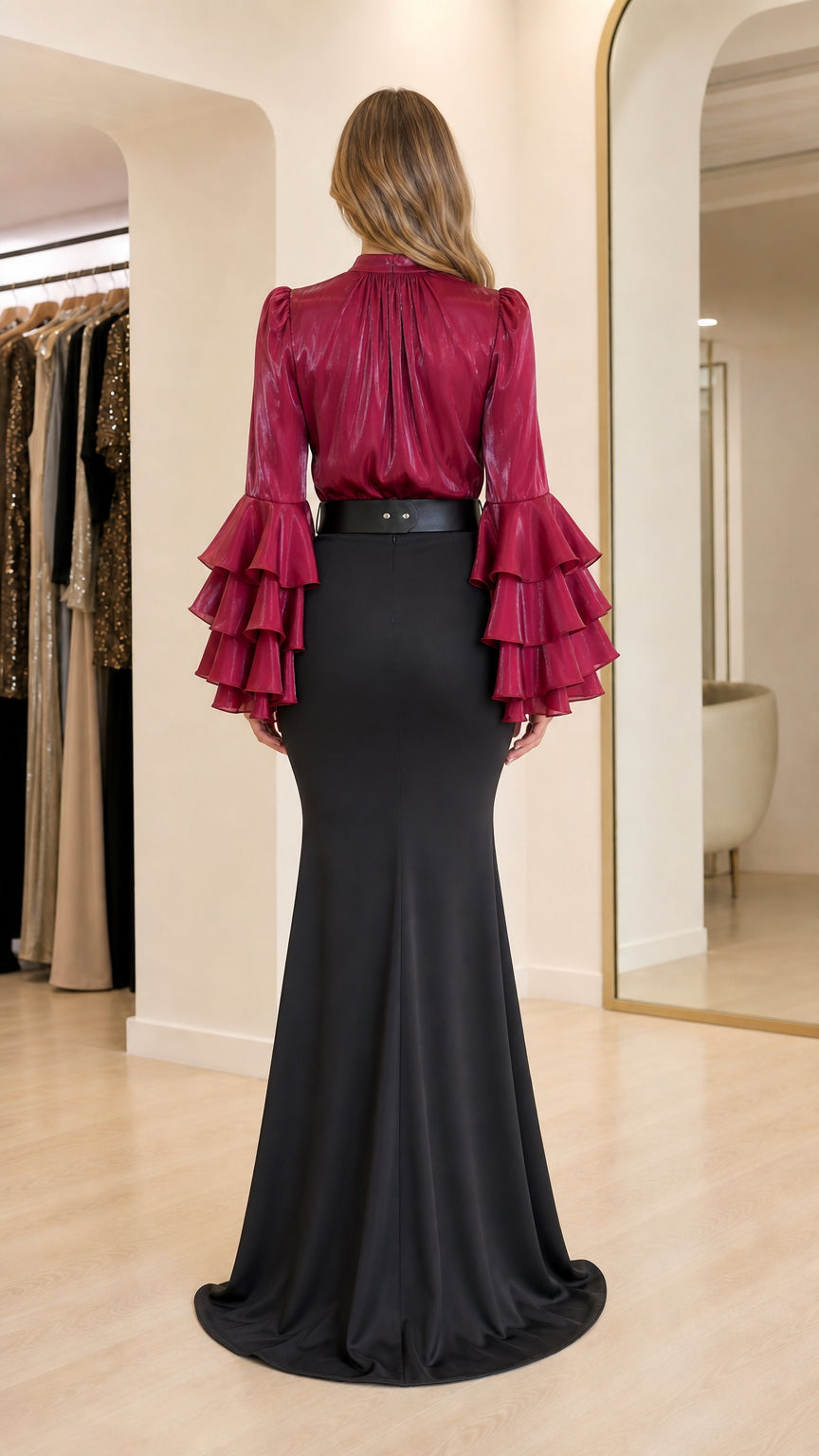 Model wearing burgundy ruffle sleeve blouse and black mermaid skirt back view