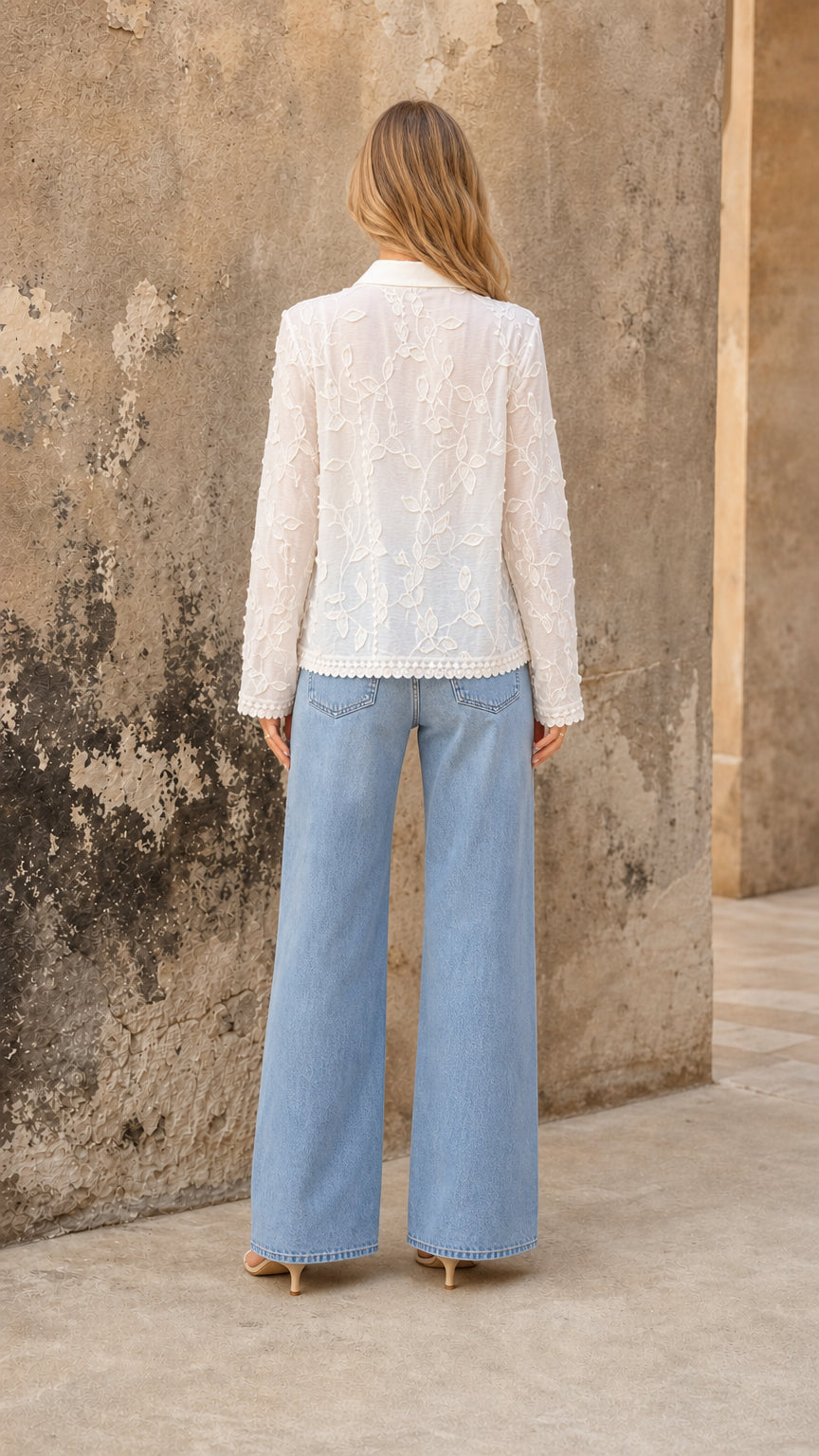 Back view showing floral embroidery and hip-length hem on white blouse