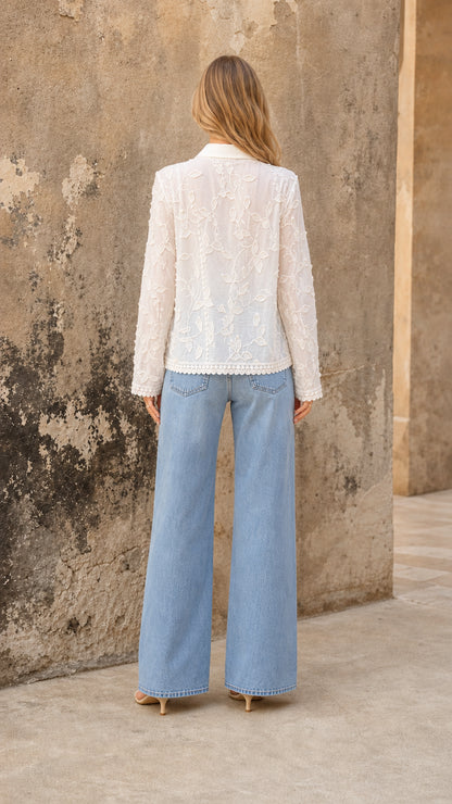 Back view showing floral embroidery and hip-length hem on white blouse