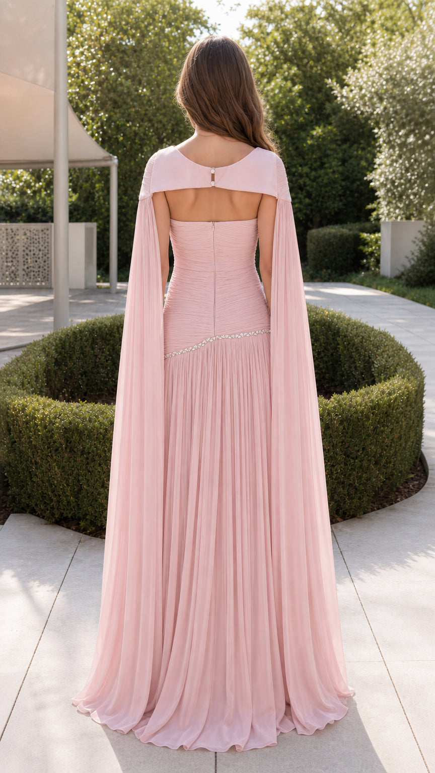 Back view of woman showing open cutout back and flowing cape on blush pink evening gown