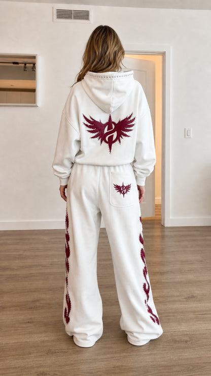 Back view of model wearing white graphic hooded sweatshirt and matching sweatpants