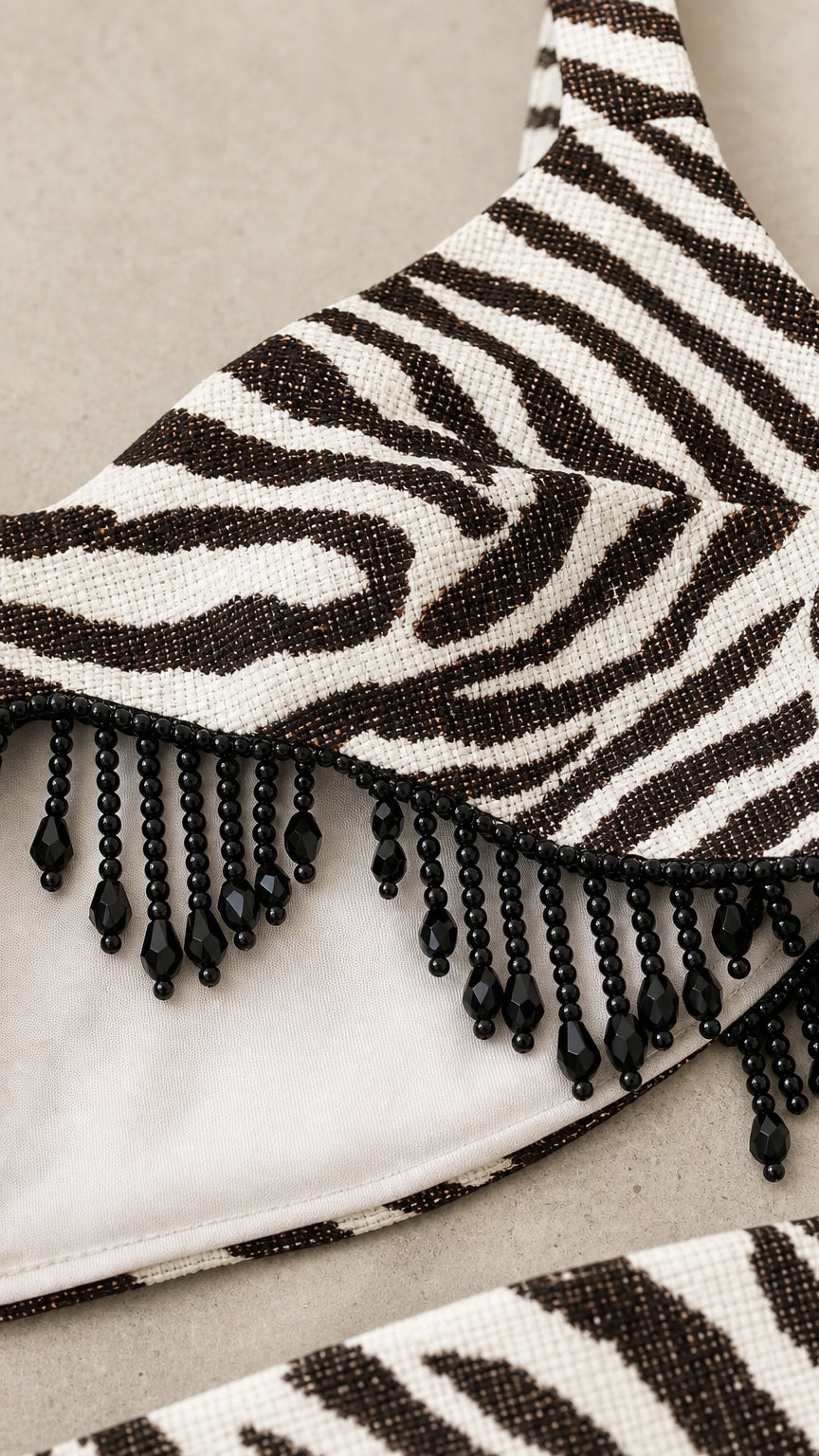 Close-up detail of black beaded fringe trim on zebra print fabric