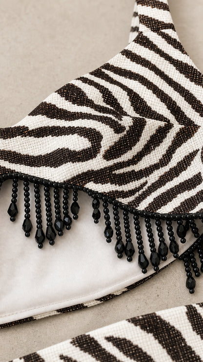 Close-up detail of black beaded fringe trim on zebra print fabric