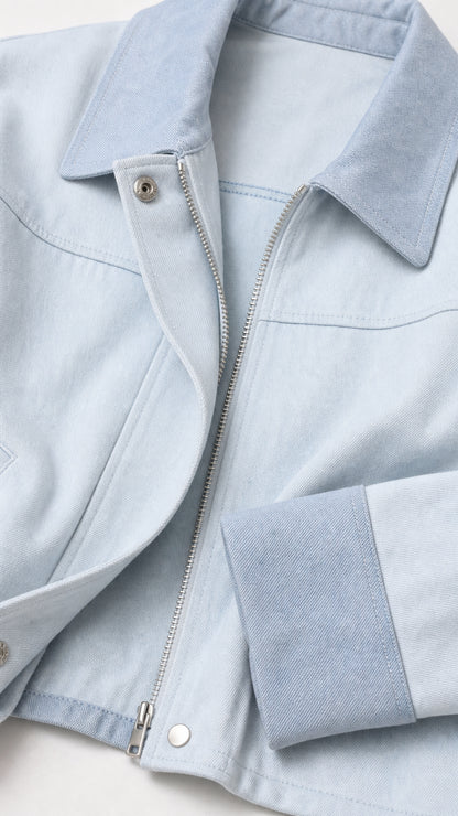 Close-up detail of light blue jacket showing metal zipper, snap buttons, and textured contrast collar