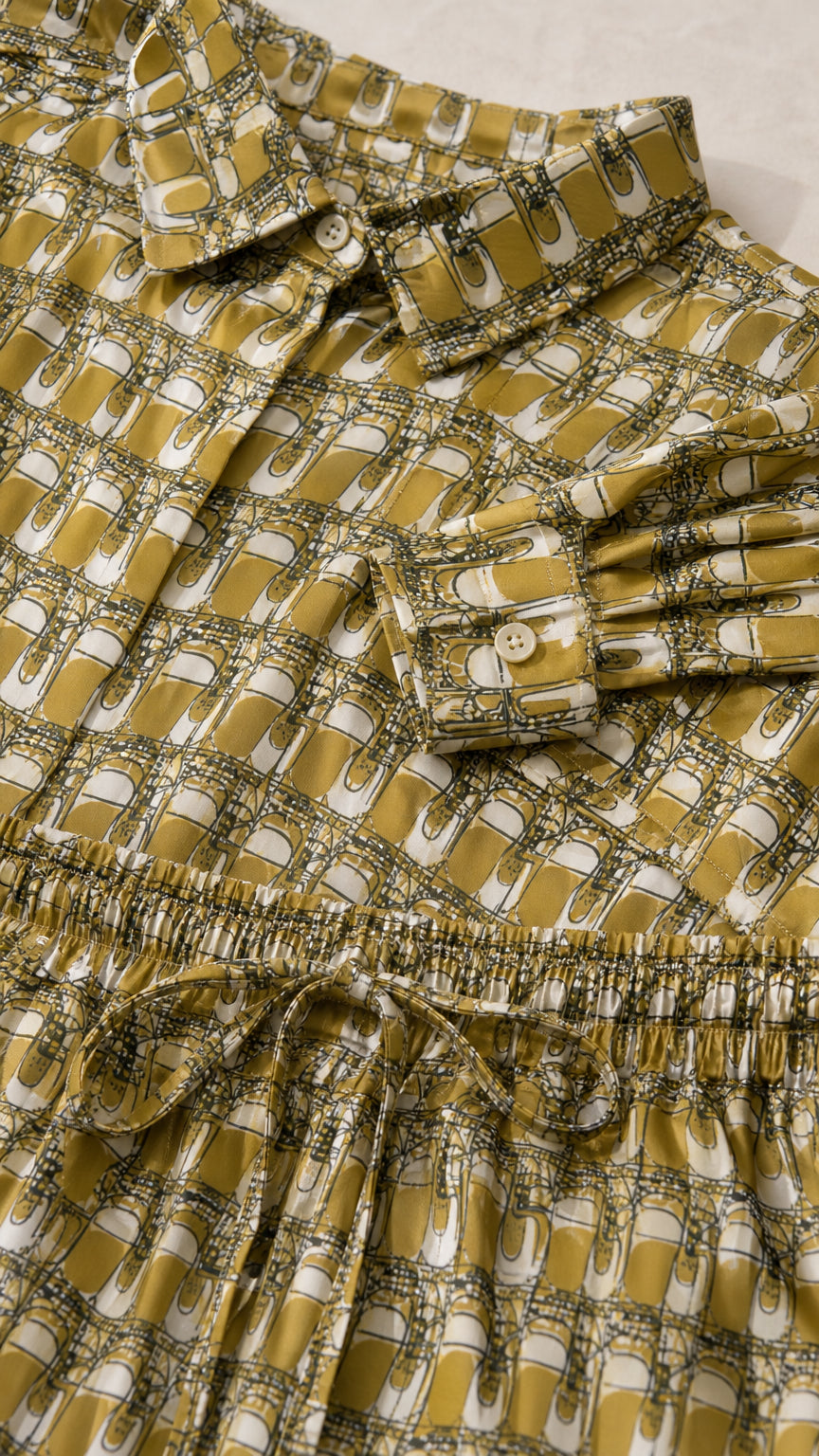 Close-up detail of the collar, button closure, and geometric pattern on the olive shirt