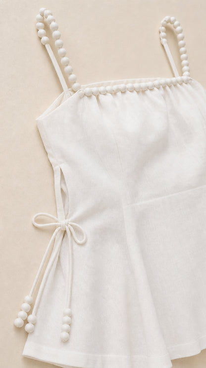 Close-up detail of white beaded straps and side tie