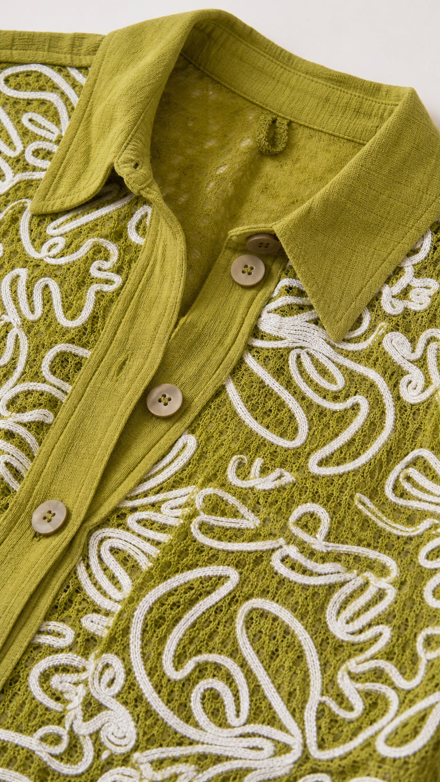 Close-up detail of collar, buttons, and embroidery on olive shirt