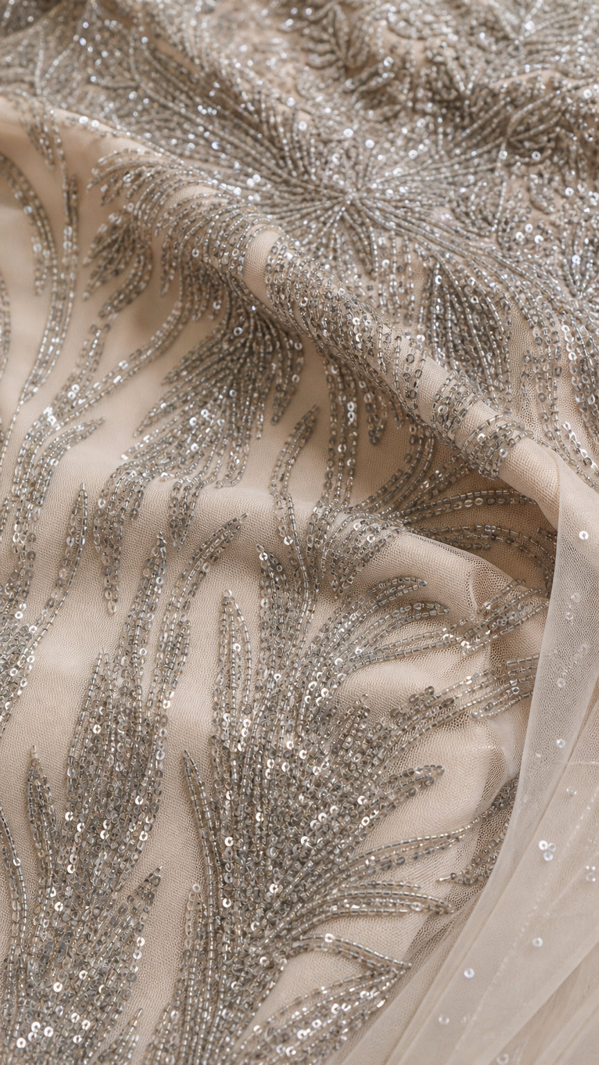 Close-up detail of intricate silver sequin and bead embroidery on fine mesh fabric