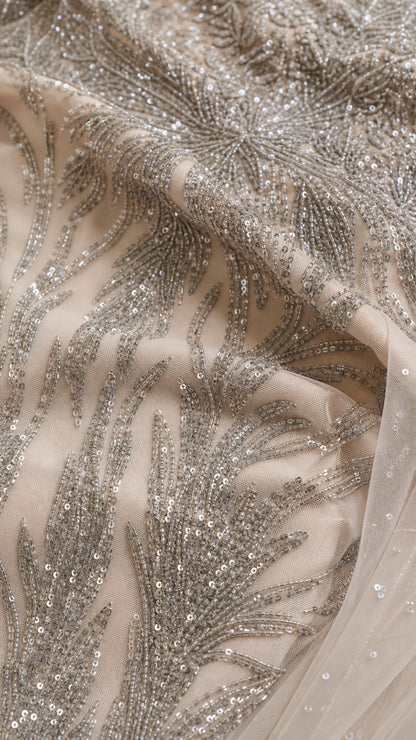 Close-up detail of intricate silver sequin and bead embroidery on fine mesh fabric