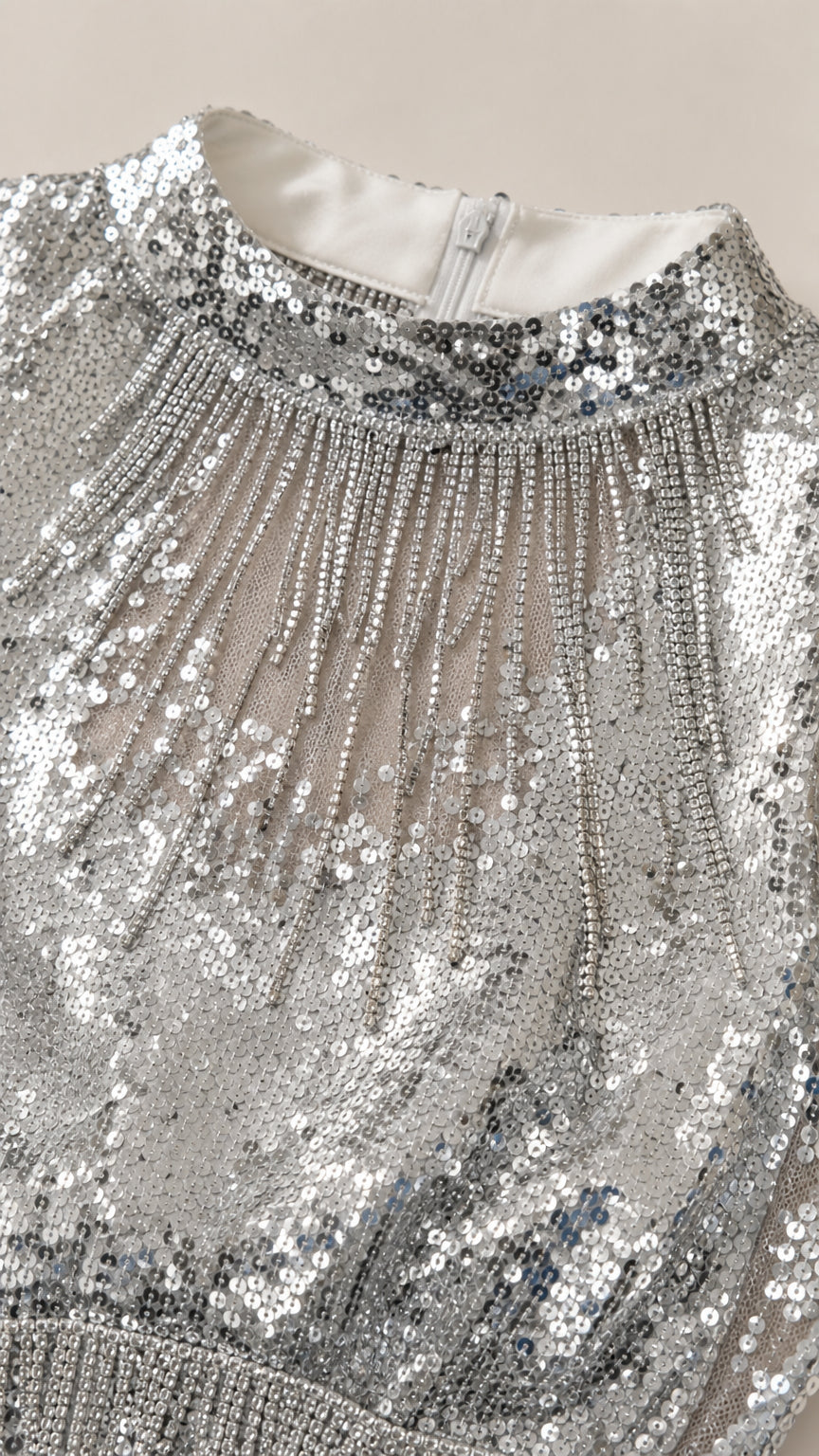 Close-up detail of silver sequin high neckline and fringe embellishment with zipper