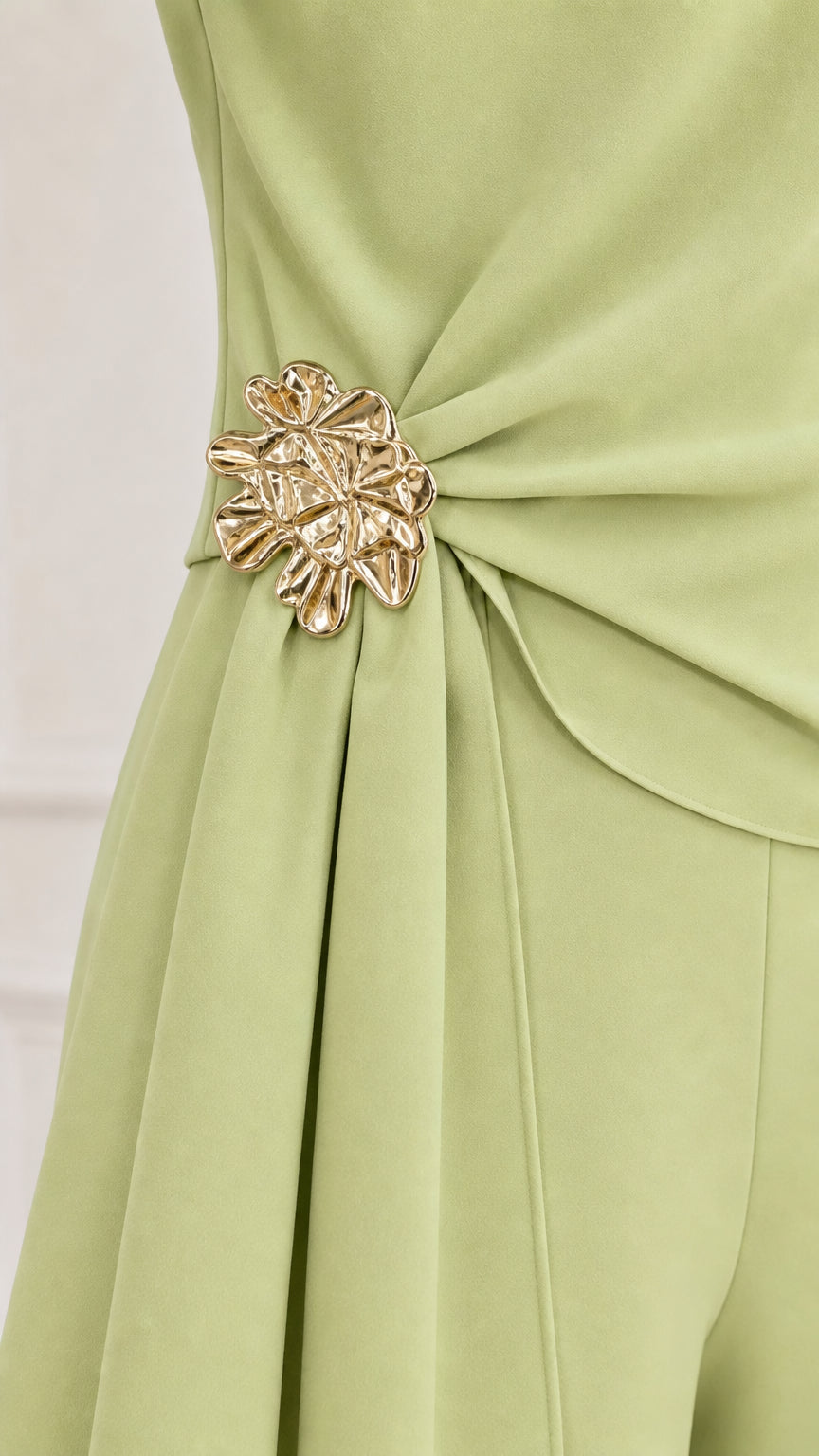 Close-up detail of metallic floral waist accent on sage green top