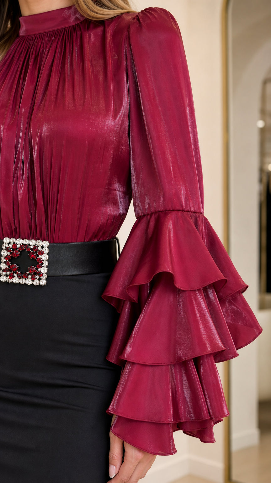 Close-up of burgundy tiered ruffle sleeve and jeweled belt buckle