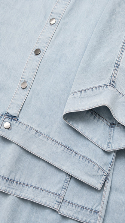 Close-up detail of light blue fabric, buttons, and seaming on shirt