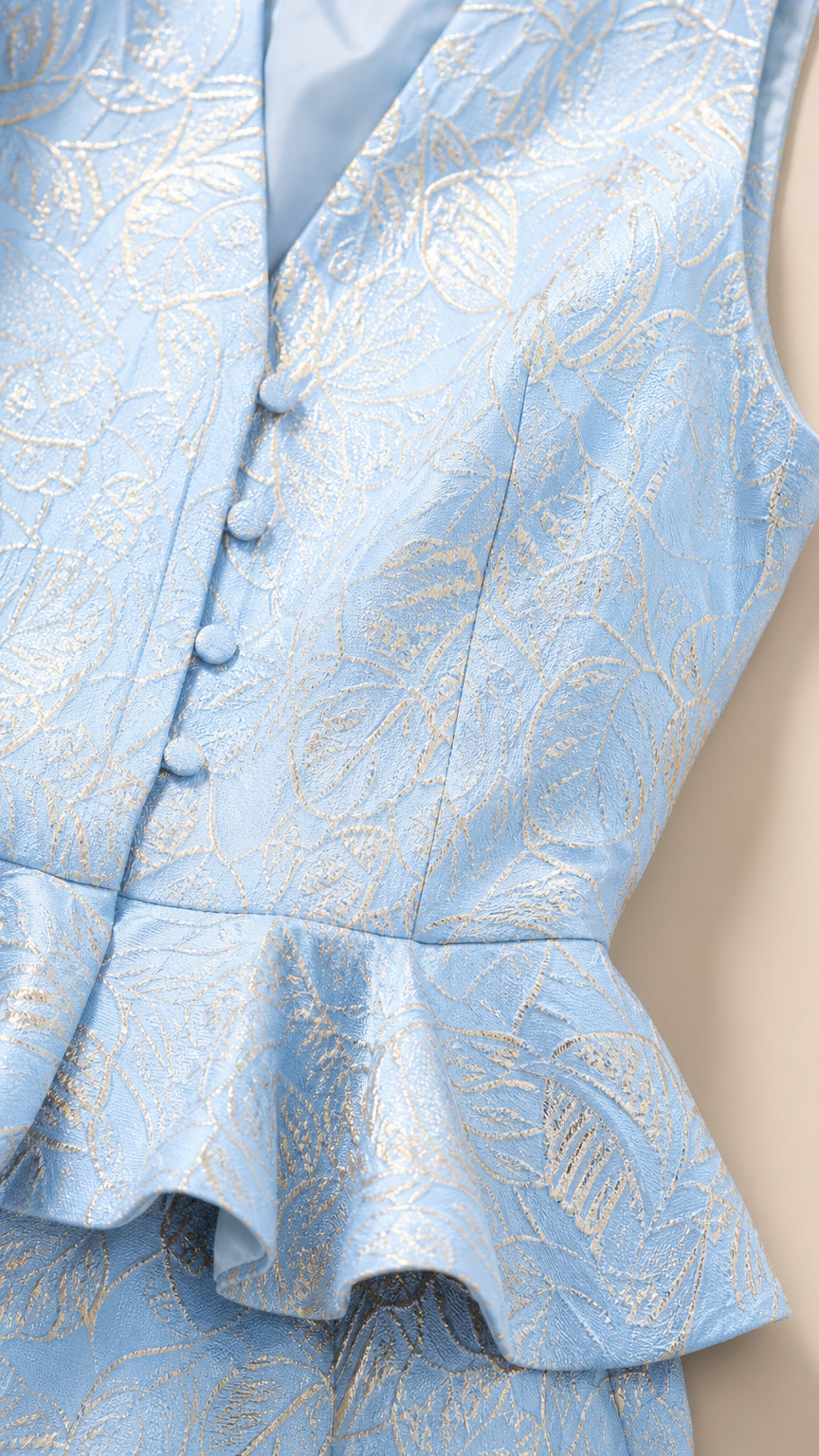 Close-up detail of covered buttons and peplum hem on Light Blue vest