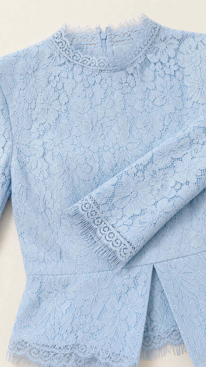 Close-up detail of light blue floral lace fabric, mock neck eyelash trim, and peplum slit