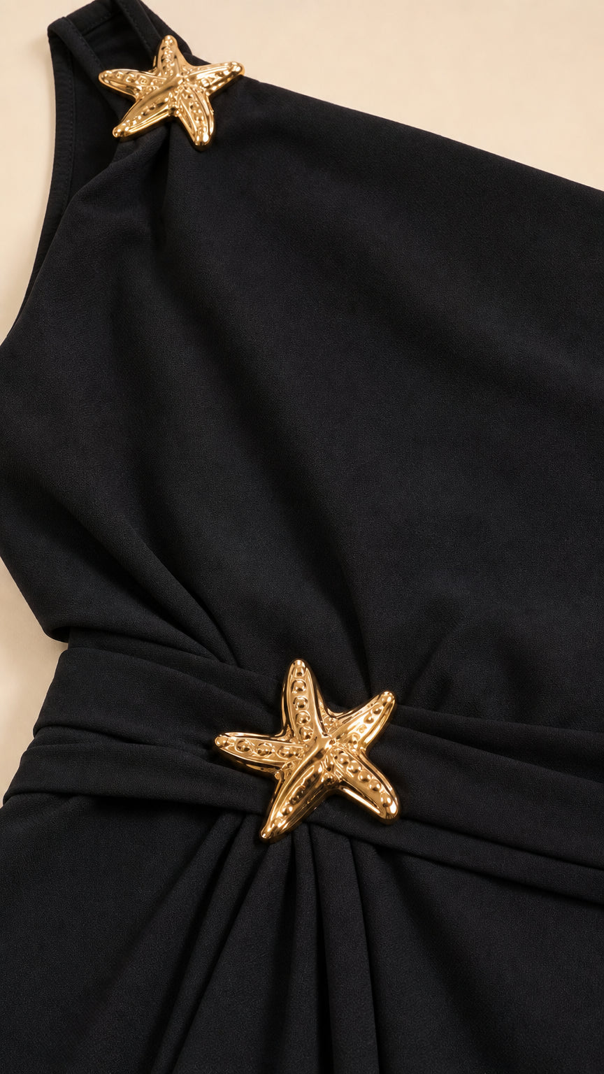 Close-up detail of black fabric with gold-tone starfish hardware at shoulder and waist