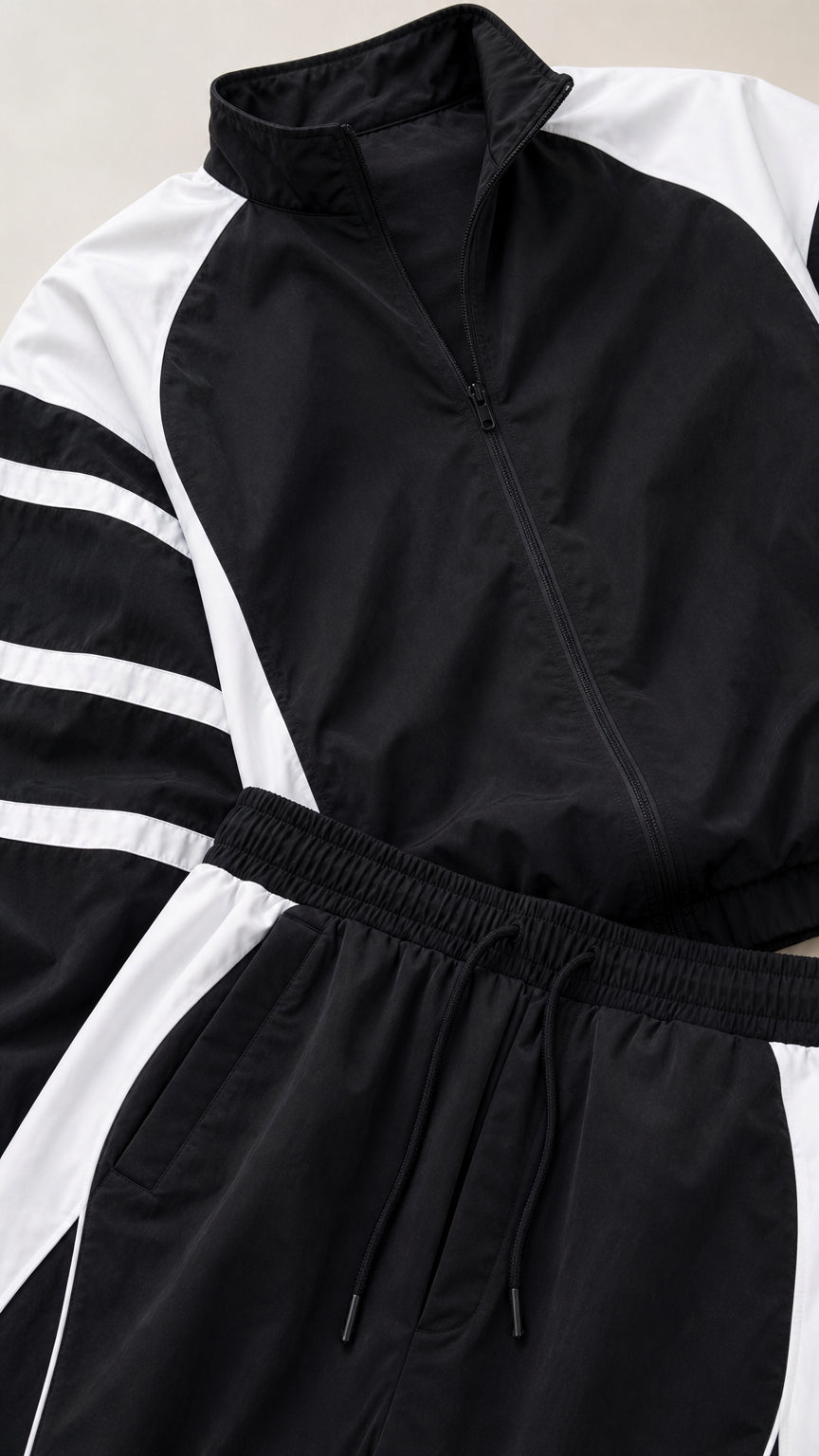 Close-up detail of black track jacket collar, zipper, and elastic drawstring waistband