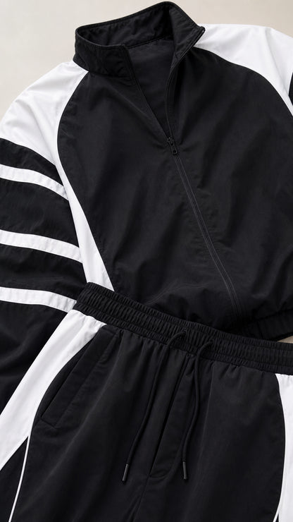 Close-up detail of black track jacket collar, zipper, and elastic drawstring waistband