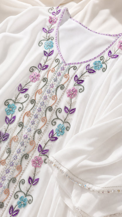 Close up of colorful floral embroidery and beadwork on white chiffon dress