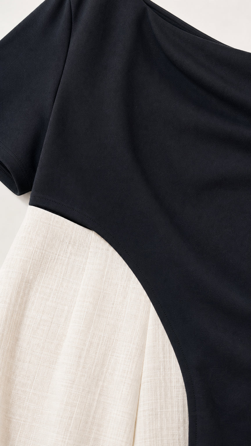 Close-up detail of fabric and asymmetrical seam on black jumpsuit