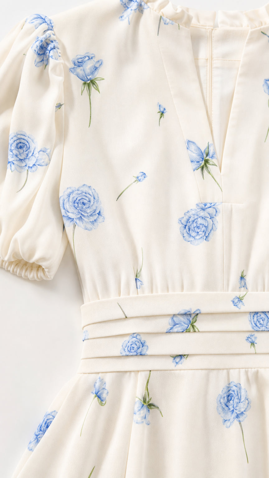 Close-up of ivory fabric, blue floral print, puff sleeve, and waist detail