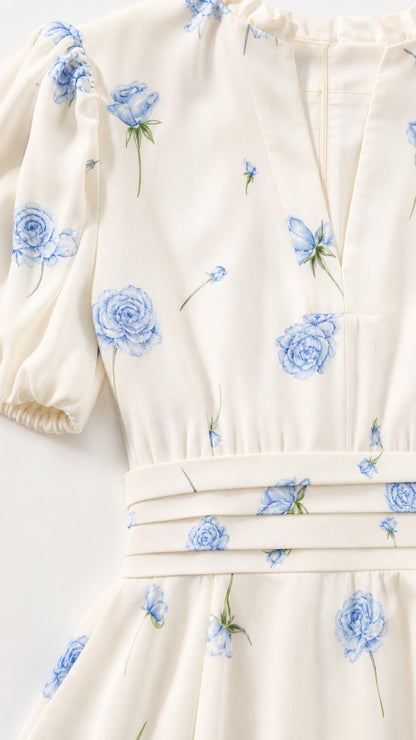 Close-up of ivory fabric, blue floral print, puff sleeve, and waist detail
