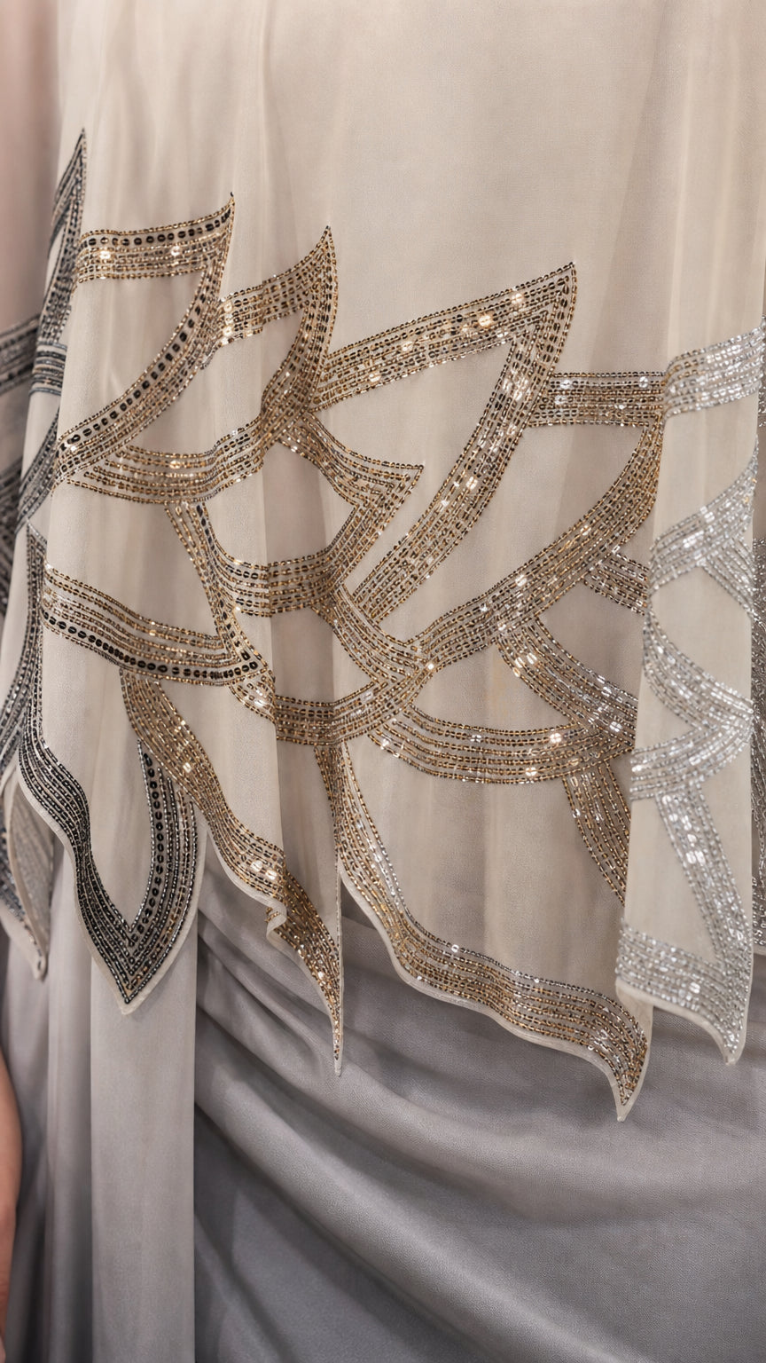Close-up detail of the intricate sequin and bead pattern on the cape overlay