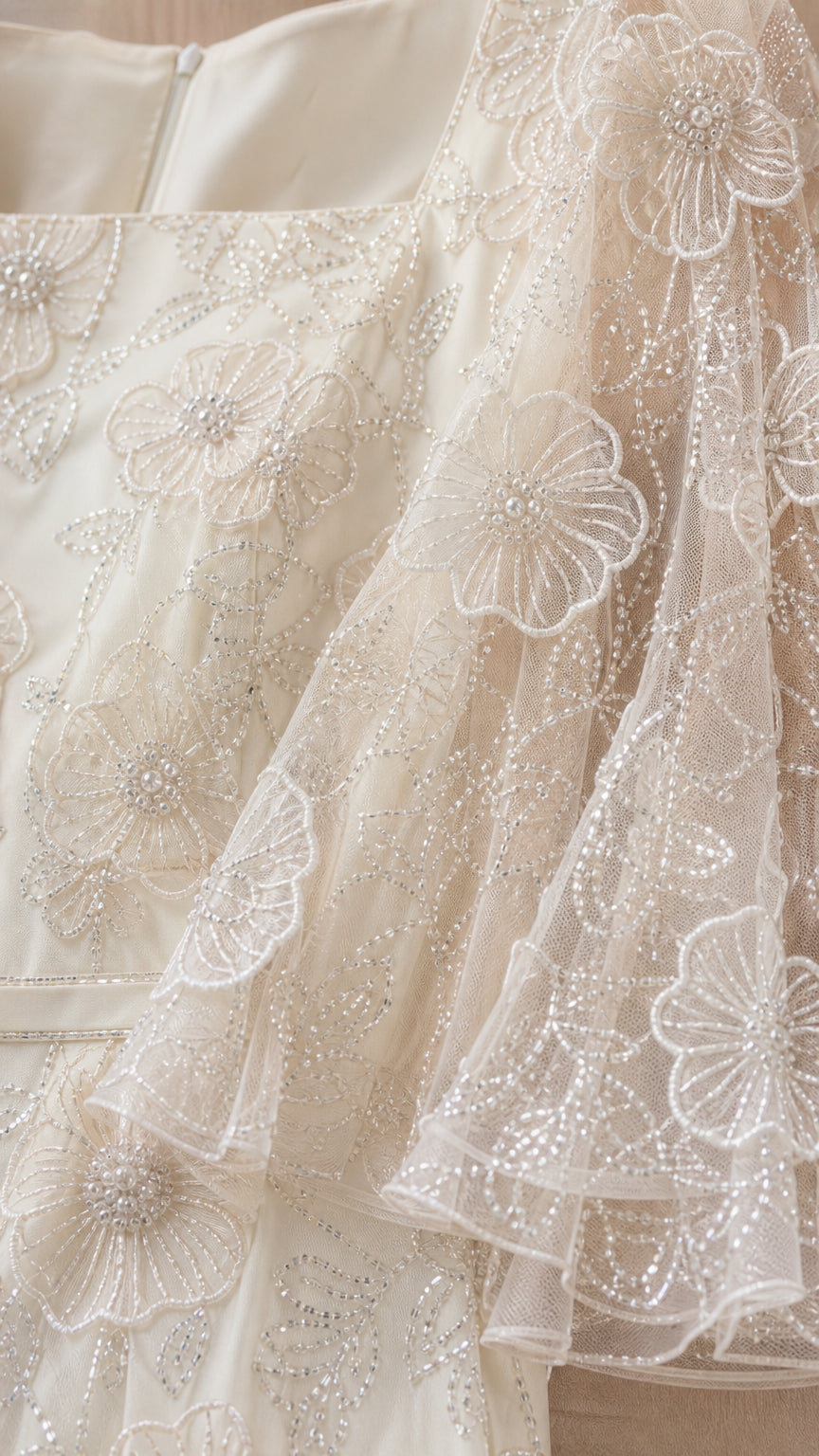 Close-up detail of floral appliques and square neckline on champagne dress