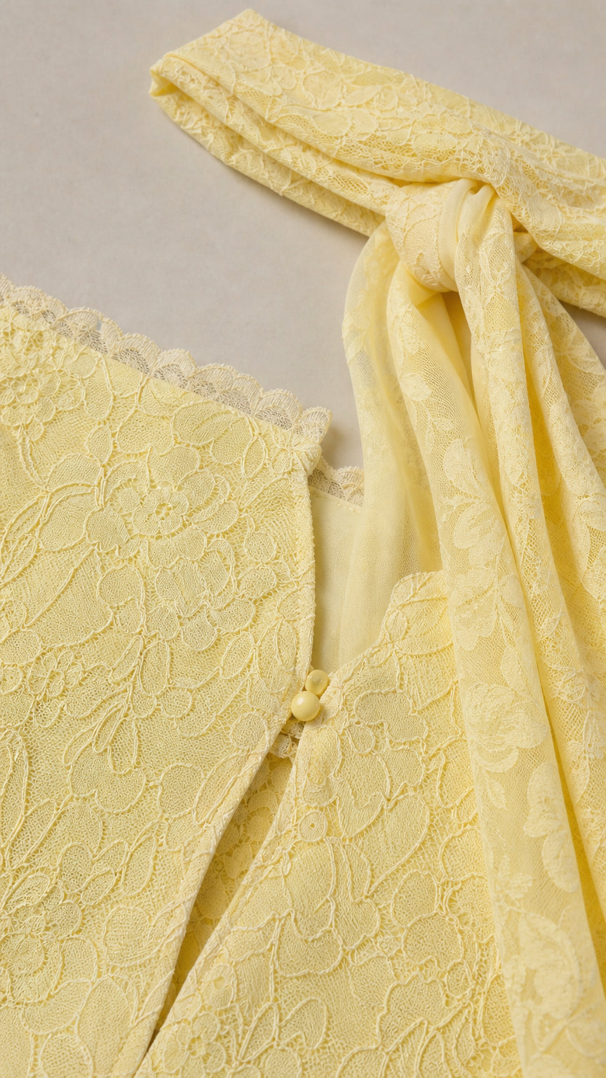 Close-up detail of lace texture and button closure on yellow dress