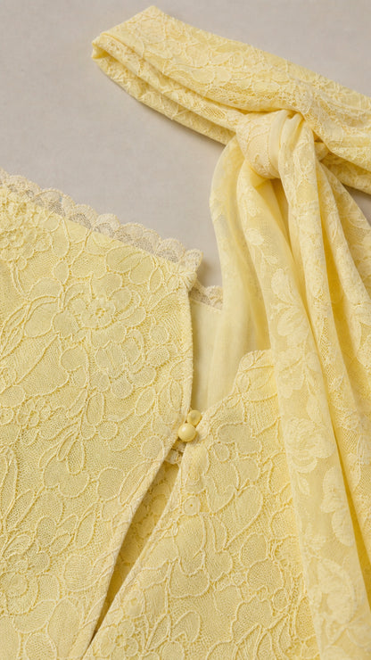 Close-up detail of lace texture and button closure on yellow dress