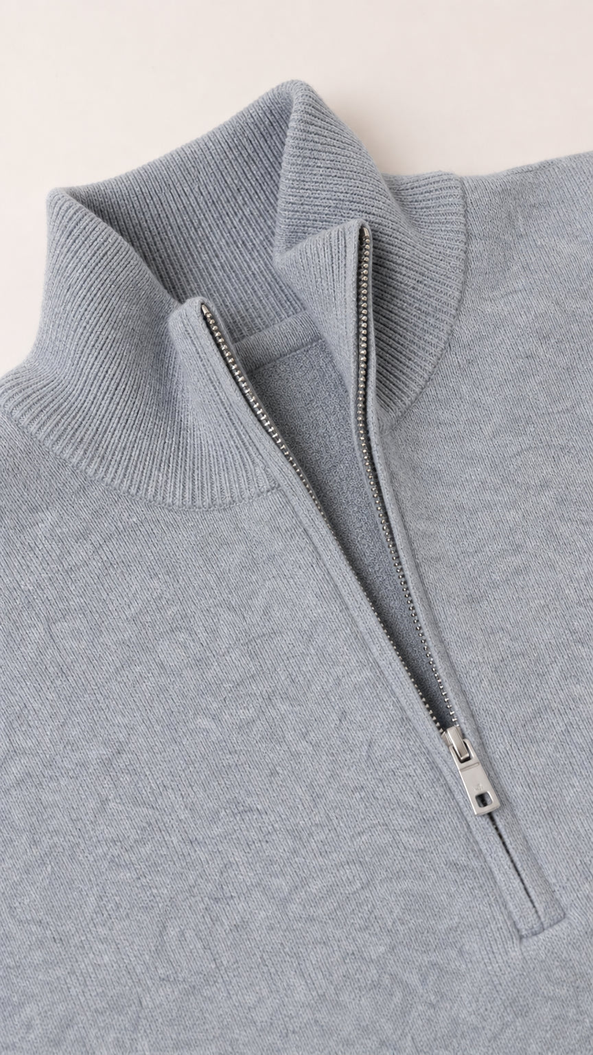 Close-up detail of soft grey knit sweater collar, ribbed texture, and silver half zipper