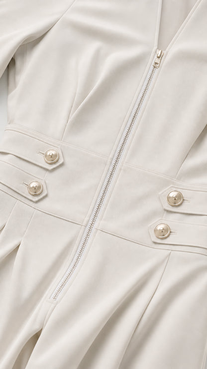 Close-up detail of cream jumpsuit metal zipper and buttoned waist tabs
