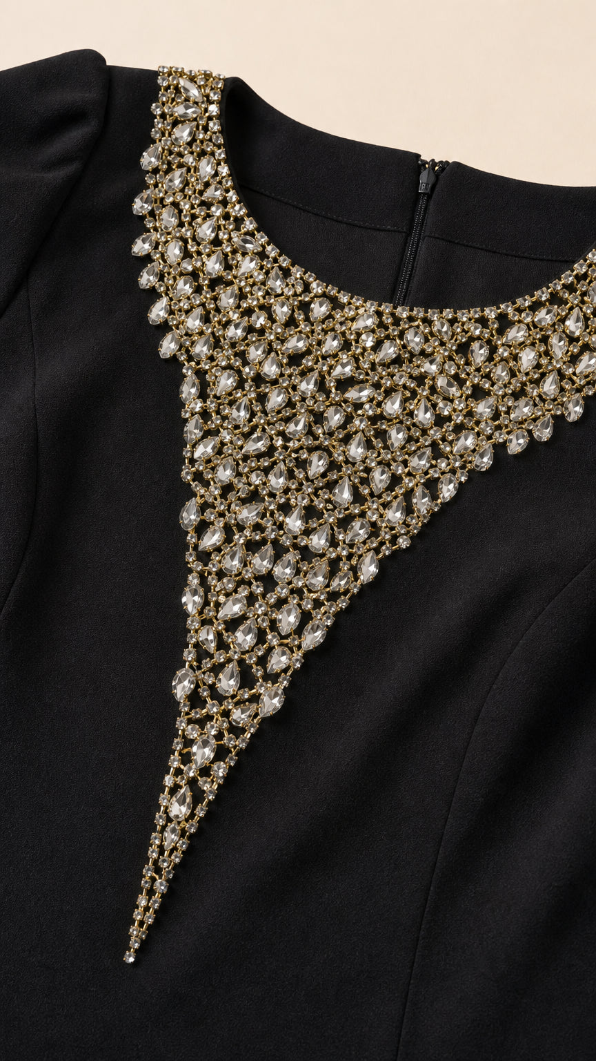 Close-up detail of sparkling crystal and rhinestone beading on the neckline of the black formal dress