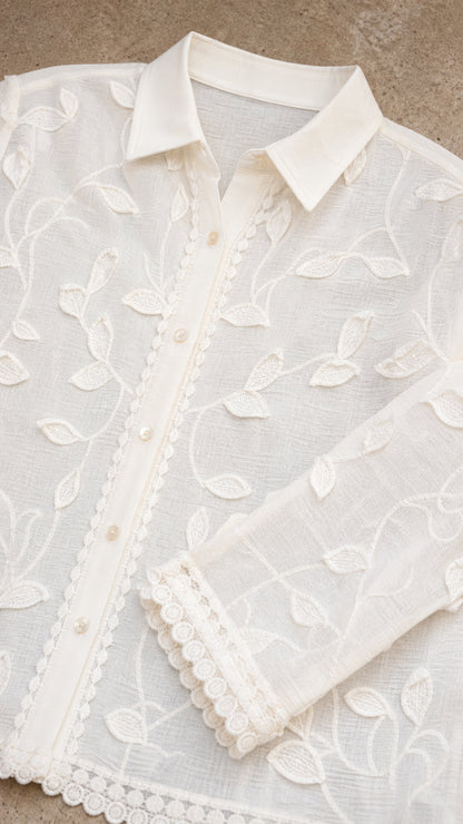 Close-up of pointed collar, button placket, floral embroidery, and scalloped trim