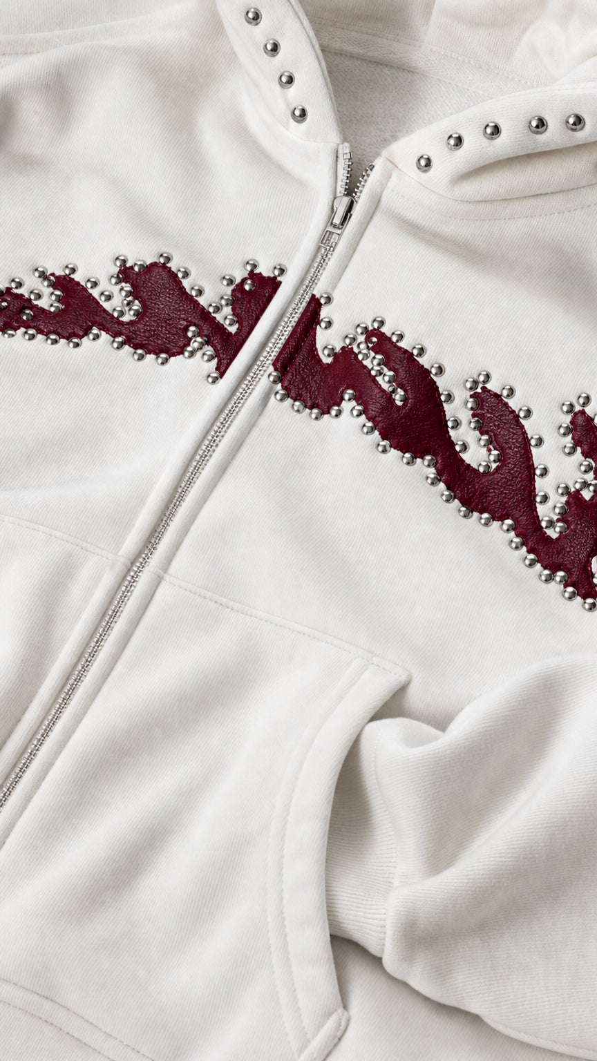 Close up view of studded hood rim and textured chest embroidery on white zip hoodie