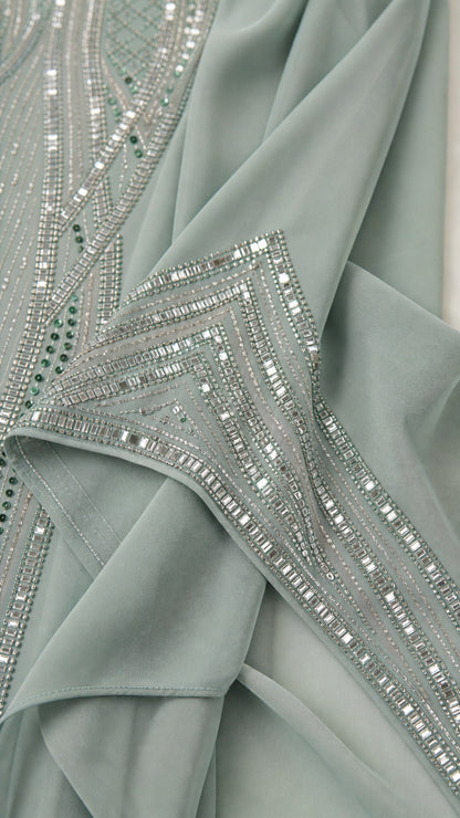 Close-up detail of geometric rhinestone embellishments on sage green fabric