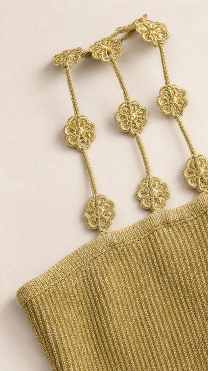 Close-up detail of metallic knit fabric and gold floral chain shoulder straps