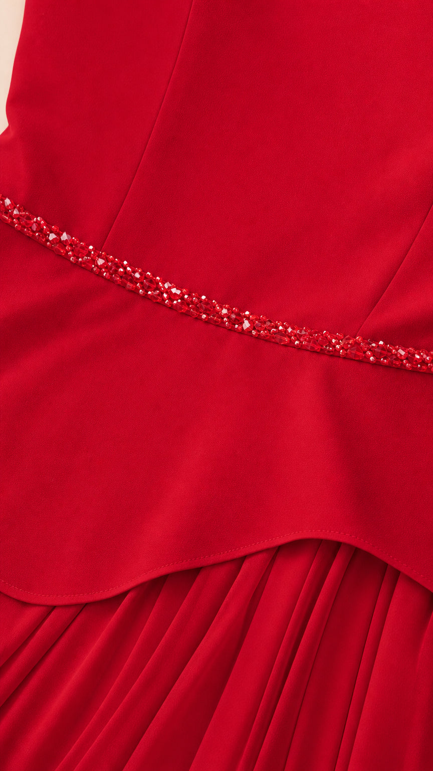 Close up of beaded waistband and peplum hem on red gown