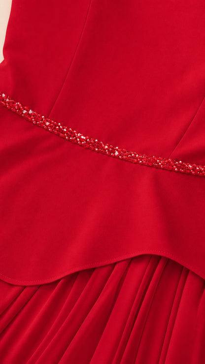 Close up of beaded waistband and peplum hem on red gown