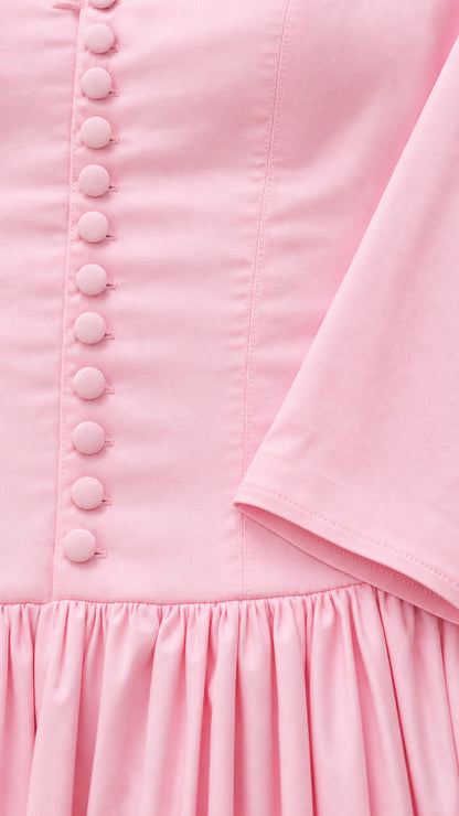 Close-up detail of covered buttons, smooth pink fabric, and gathered waistline
